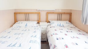 A twin room with two beds, a nightstand, and a painting of a beach scene.