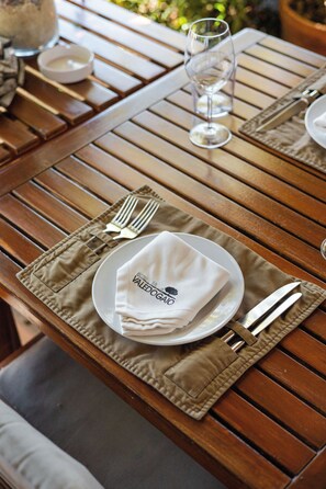 Una mesa de madera dispuesta para comer, con un plato, servilleta, tenedor, cuchillo y vaso.