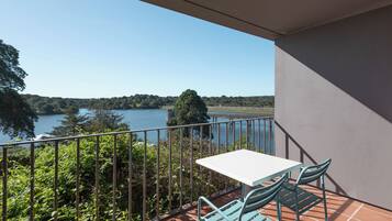 A balcony with a table and chairs overlooking a lake.