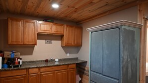 A kitchen with wooden cabinets, a granite countertop, and a refrigerator. - Alaska River Pirates Cabins (Soldotna)