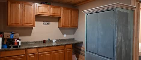 A kitchen with wooden cabinets, a granite countertop, and a refrigerator.