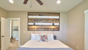 A bedroom with a large bed, a wooden headboard, and two wall-mounted lights.