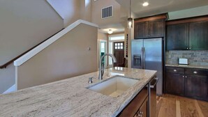 A kitchen with a granite countertop, stainless steel appliances, and dark wooden cabinets.