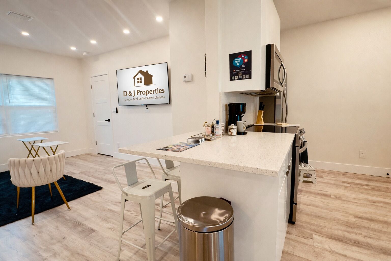 Een moderne keuken met een centraal eiland, barkrukken, een koffieapparaat en een koelkast.