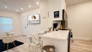 A modern kitchen with a central island, bar stools, a coffee machine, and a refrigerator. - Daytona Double Delight (Daytona Beach)