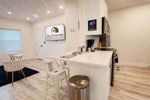 A modern kitchen with a central island, bar stools, a coffee machine, and a refrigerator. - Daytona Double Delight (Daytona Beach)