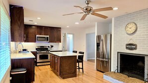 A modern kitchen with wooden cabinets, stainless steel appliances, and a central island. - Tranquil Ranch Style Retreat w/ 2+ Acres of Land (Marietta)