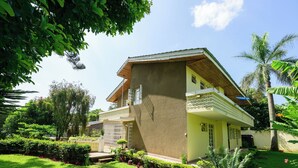 A two-story house with a sloped roof, surrounded by lush greenery and a well-maintained garden. - 5-bedroom bed & breakfast in charming Arusha with WiFi (Arusha)