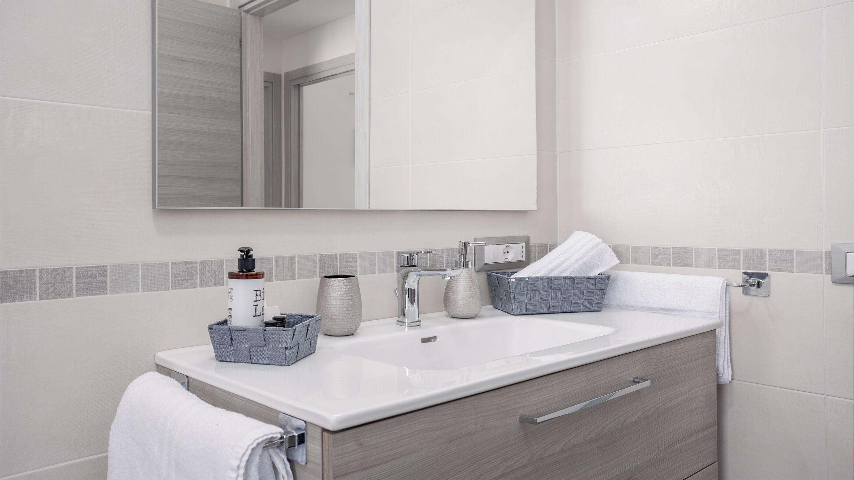 Une salle de bain moderne avec un lavabo blanc, un miroir et un meuble en bois.