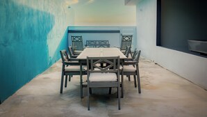 A dining area with a table and chairs, a blue wall, and a large window. - Salt Water Private Pool House W/ Ocean View, WiFi, Air Cond, Generator, Solar E. (Naguabo)