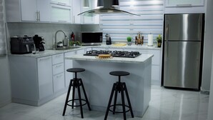 A modern kitchen with a central island, stainless steel appliances, and black bar stools. - Salt Water Private Pool House W/ Ocean View, WiFi, Air Cond, Generator, Solar E. (Naguabo)