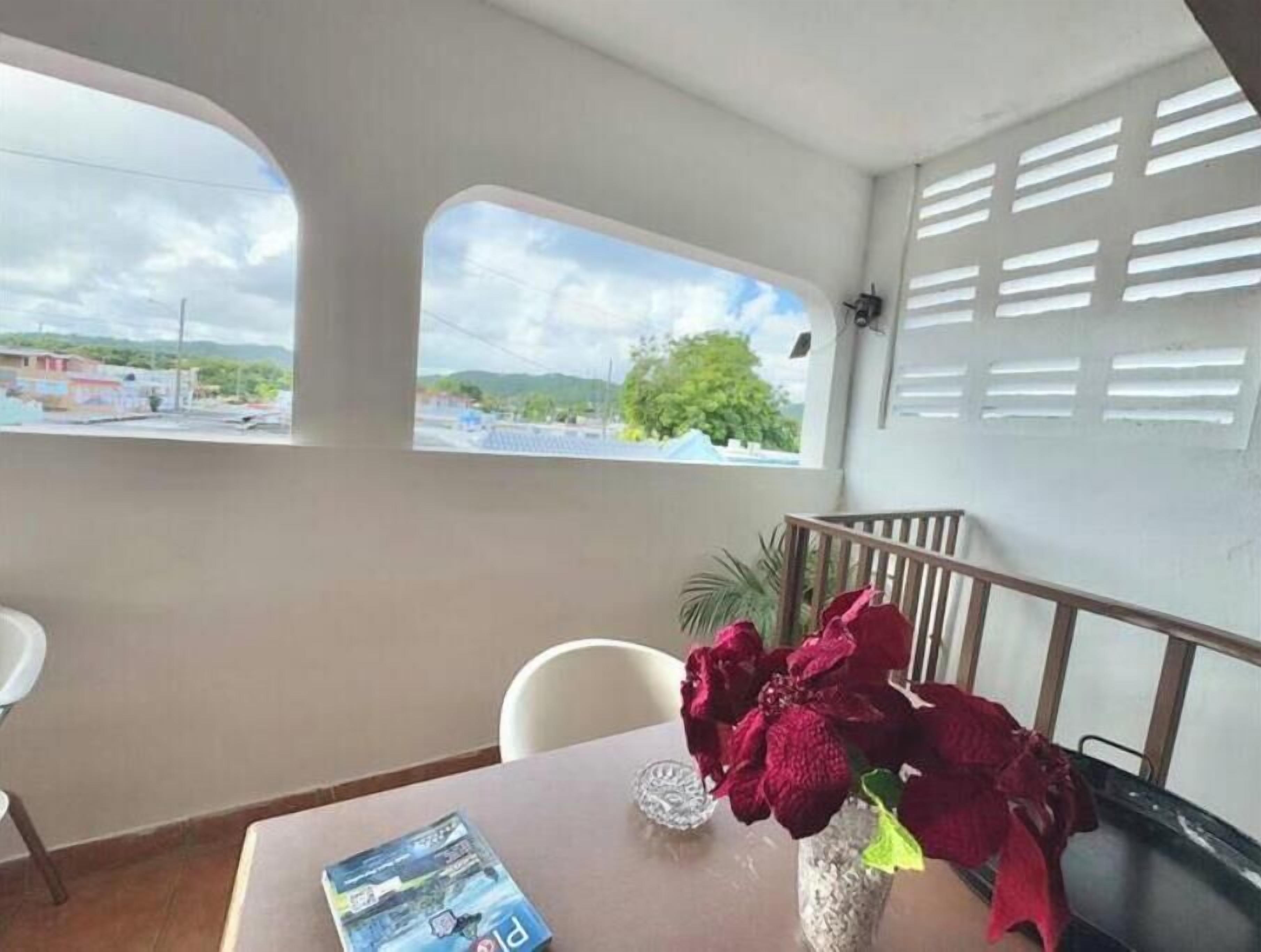 A room with a table, a chair, a vase with flowers, and a view of the outside.