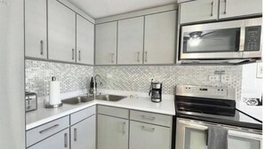 A modern kitchen with stainless steel appliances, a double sink, and a microwave. - Quiet & comfortable, 3/2, 5 beds free parking, sleep 9 (Ceiba)
