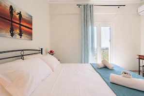 A hotel room with a bed, a painting, a window with curtains, and a view of the outside.