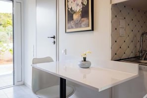 A modern kitchen with a white countertop, a vase with flowers, and a tiled backsplash.