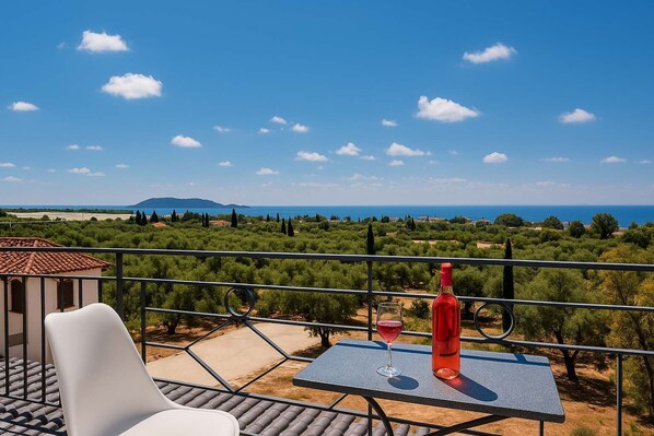 A balcony with a table, a chair, a bottle, and a glass.