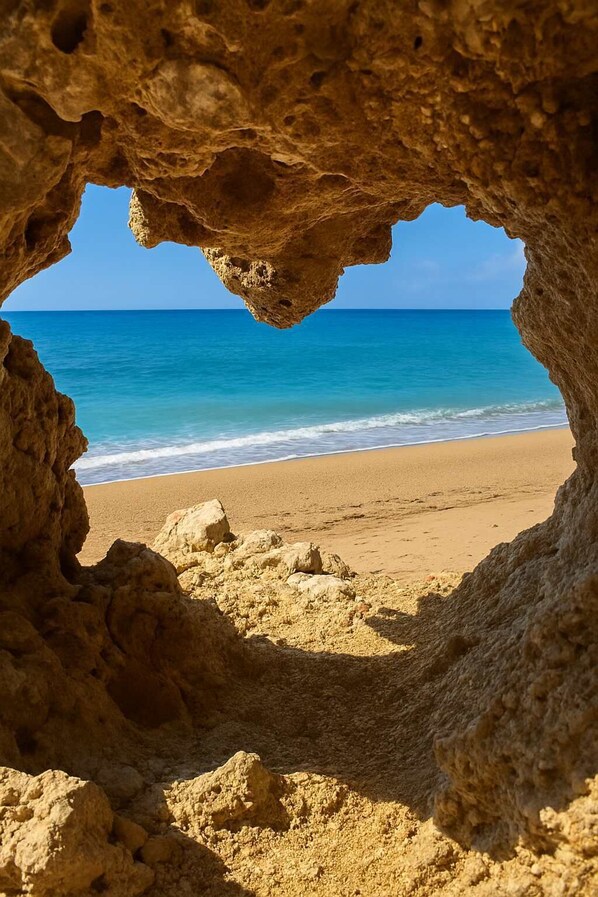 A beach view through a rocky cave entrance.