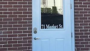 Une porte blanche avec un panneau en verre, portant l’adresse « 71, rue Market ».