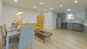 A modern apartment with a dining area, a sofa, a kitchen with appliances, and a laundry area. - Beauchamp House, 2-bed apartment Covstays (Coventry)