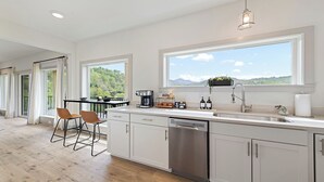 A modern kitchen with a large window, a coffee machine, and a dishwasher.
