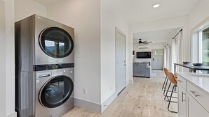 A modern kitchen with stainless steel appliances, a dining area with a bar stool, and a view of the outdoors.