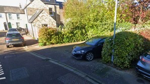 A residential street with parked cars and a stone building.