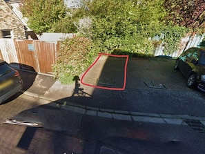 A parking area with a red boundary, a paved surface, and a brick wall.