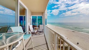 A balcony with a glass table and chairs, overlooking a beach with a clear view of the ocean and a pier in the distance. - Tidewater 408 (Panama City Beach)