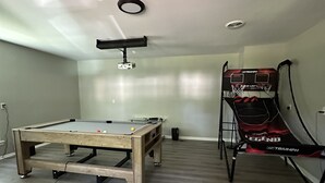 A room with a pool table, a projector, and a basketball hoop. - Pinewoods Hideaway – Quiet Comfort Near It All (Spring)