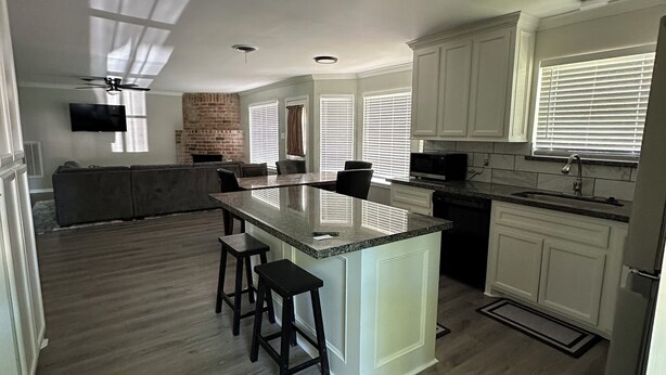 A modern kitchen with a central island, bar stools, and a fireplace. - Pinewoods Hideaway – Quiet Comfort Near It All (Spring)