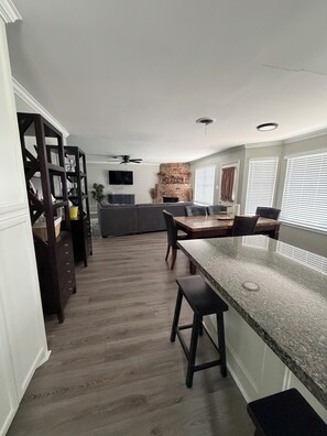 A modern kitchen with a granite countertop, dark wooden cabinets, and a built-in brick fireplace.