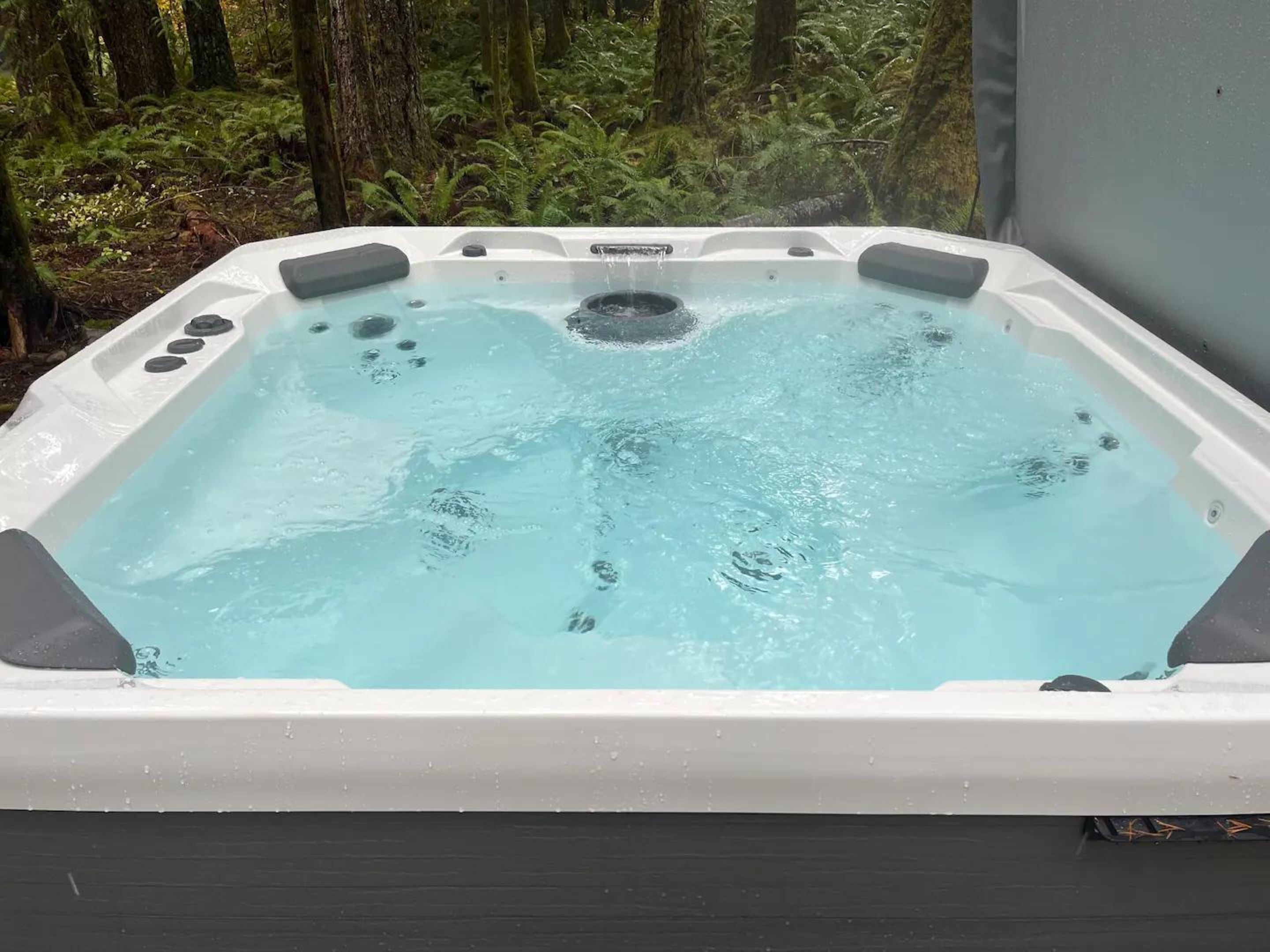 A hot tub with a clear view of the surrounding forest.