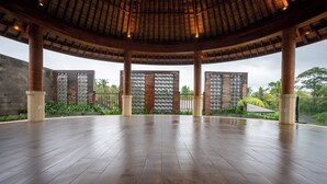 An indoor space with a high ceiling, wooden flooring, and columns. - Budhi Ayu Suite (Ubud)