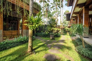 A tropical garden with a stone pathway leading to a wooden building. - Budhi Ayu Suite (Ubud)