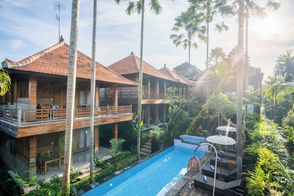 A resort with multiple wooden buildings, a swimming pool, and lush tropical vegetation. - Budhi Ayu Suite (Ubud)