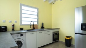A compact kitchen with a washing machine, a sink, a window, and a refrigerator.