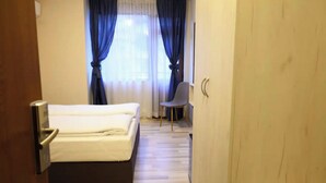 A hotel room with a bed, a chair, and a wooden floor. - Hotel Leda (Sofia)