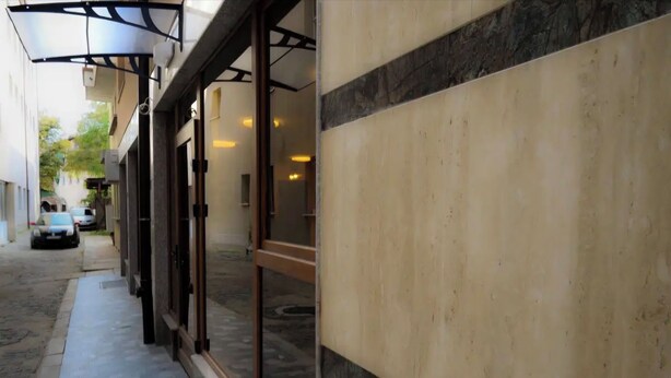 A narrow alleyway with a building entrance featuring a glass door and a metal awning. - Hotel Leda (Sofia)