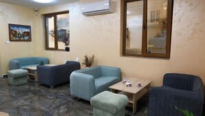 A room with a blue sofa set, a small table with a cup, and a large window with a view. - Hotel Leda (Sofia)
