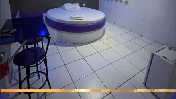 Una habitación con una cama redonda, una mesita con una silla y un equipo de aire acondicionado en la pared.