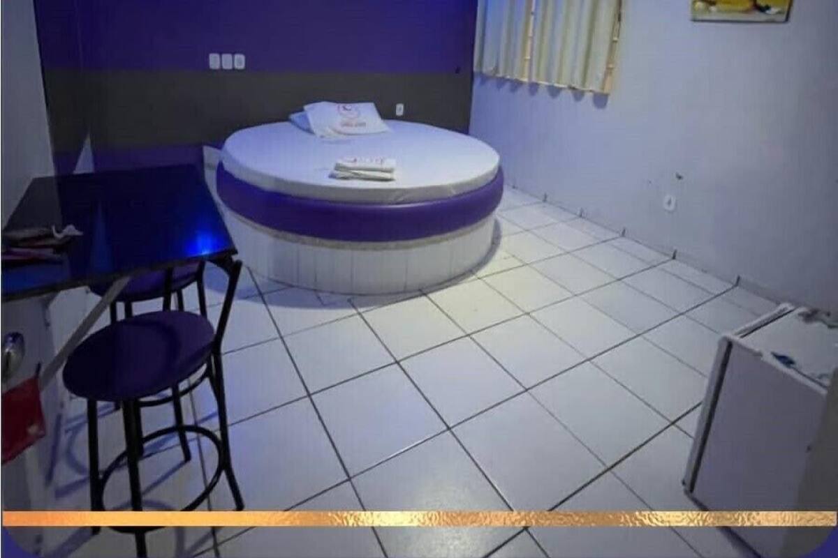 Una camera con un letto rotondo, un piccolo tavolo con una sedia e un condizionatore d'aria a parete.