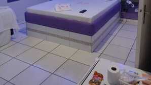 Una habitación de hotel con una cama grande, una mesita de noche con artículos de aseo y una pequeña mesa con aperitivos.