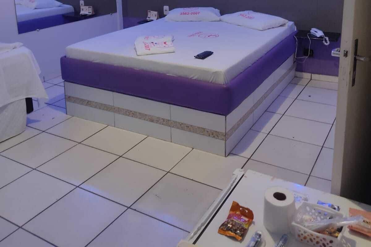 Una camera d'albergo con un letto grande, un comodino con articoli da toilette e un tavolino con qualche snack.