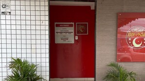 Entrada de hotel con puerta roja, letrero que indica una suite estándar y dos macetas.