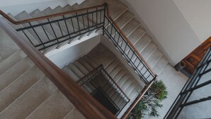 Una escalera de varios niveles con barandillas de madera y pasamanos de metal.