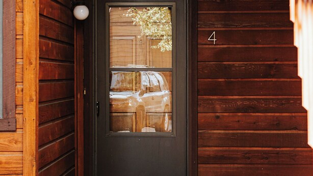 A wooden cabin with a dark door, a small porch area, and a number '4' on the wall.