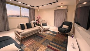 Una sala de estar moderna con un sofá, dos sillones, un tapete estampado y una zona de comedor con una mesa y sillas.