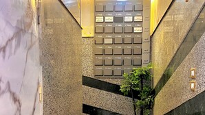 Una escalera con suelo de mármol, barandilla de metal, una planta en maceta y una pared con varios carteles en árabe.