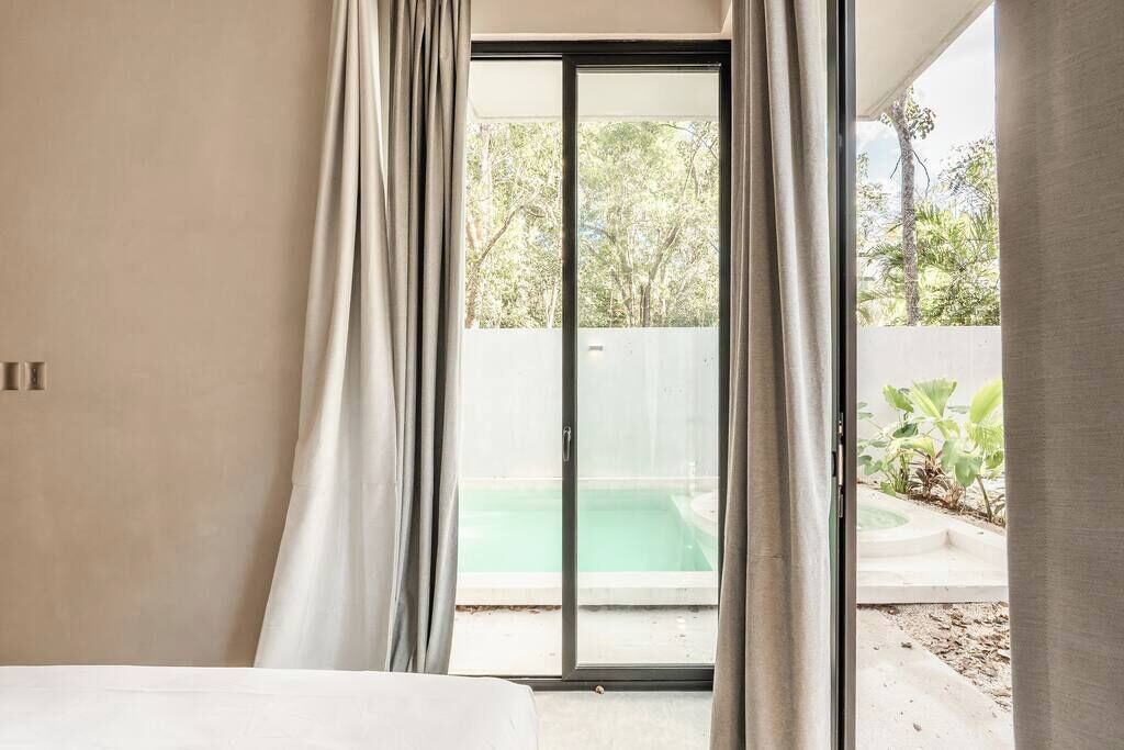 Une chambre dotée d’une grande porte-fenêtre coulissante donnant sur un espace piscine.