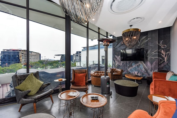Un salón moderno con sillones de cuero, chimenea y grandes ventanales con vistas a la ciudad.